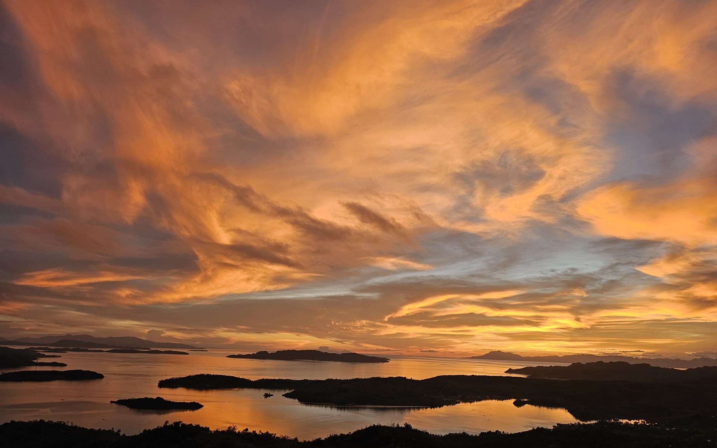 Sunset from Laaganan Skybar: orange and violet cloud over the island channel, the water below turned to gold